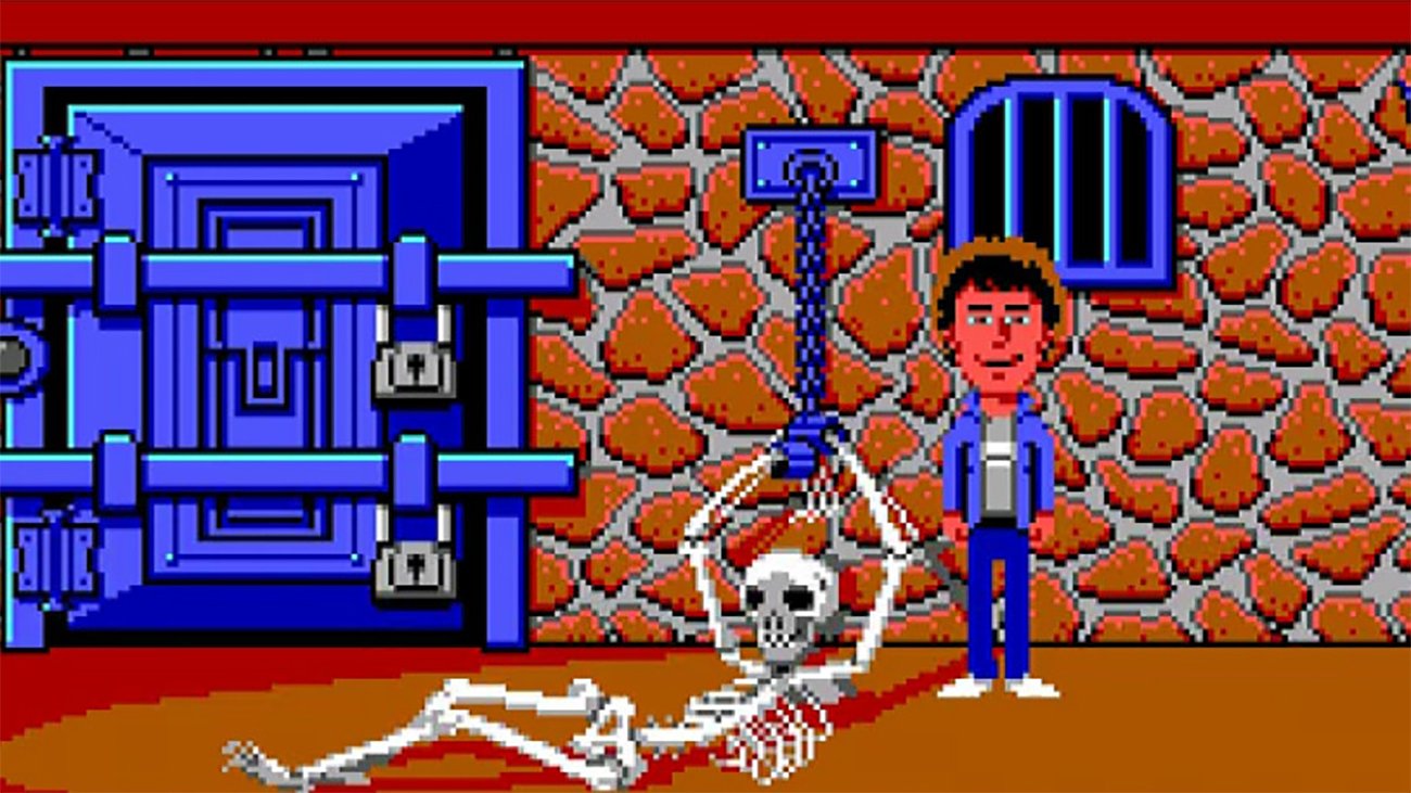 '80s adventure game Maniac Mansion with a man standing and smiling next to a skeleton chained to a wall